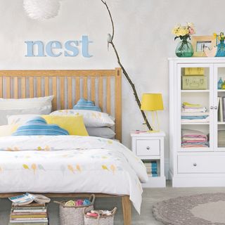 bedroom with white wall grey flooring white cupboard and wooden bed