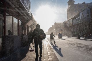 Photograph taken with Fujifilm X100V camera, backlit silhouetted figure in snowy street