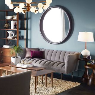 grey sofa, big round mirror, blue walls, lots of lighting