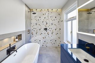 An example of shower tile ideas showing Terrazzo tiles in a shower room with a white bath and sink