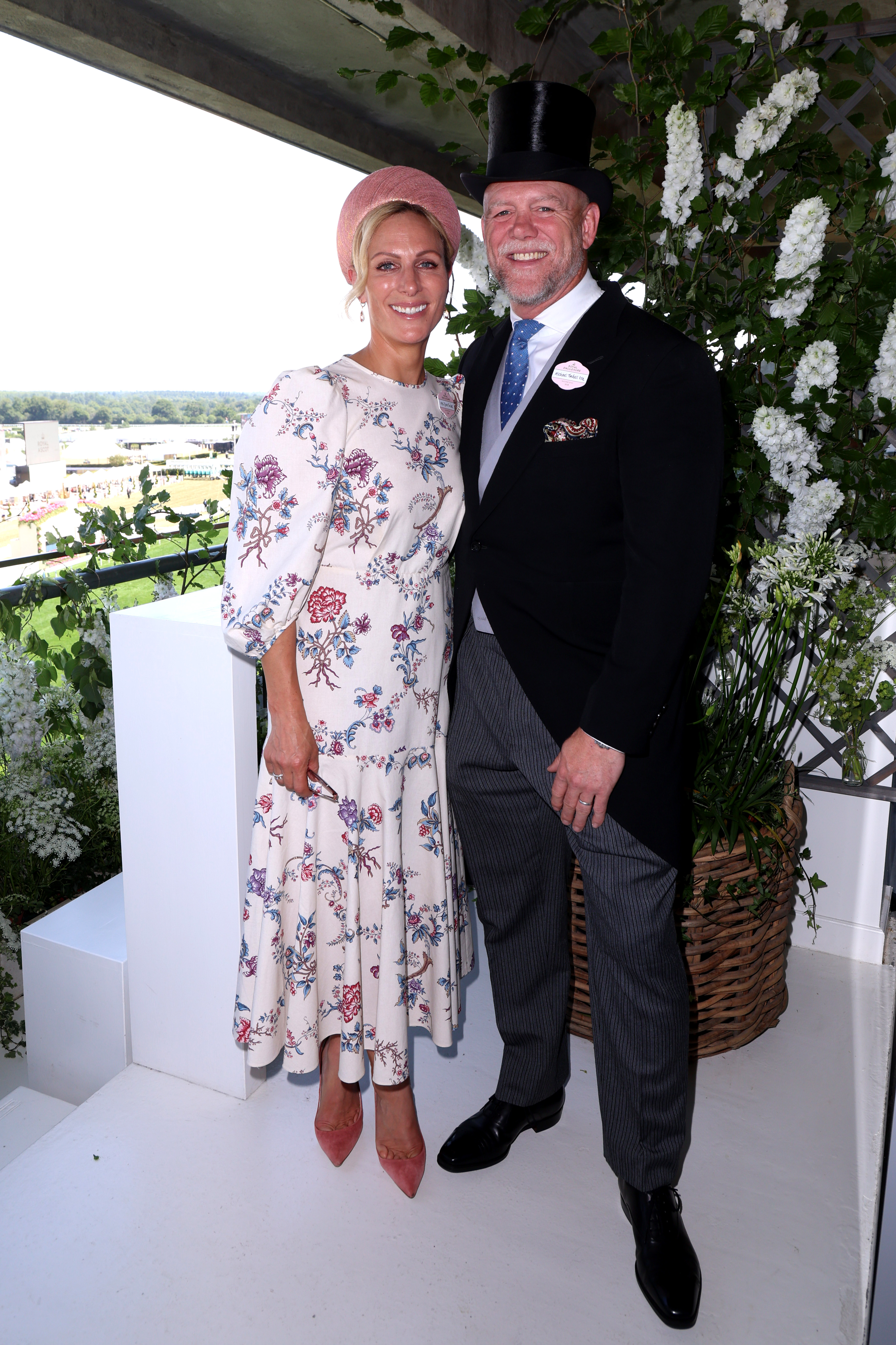 Zara Tindall wearing a white floral Anna Mason dress posing with husband Mike Tindall, in a suit and top hat