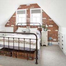 bedroom with brick wall and bedside table with lamp and carpet on floor 