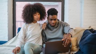 Couple looking at laptop on sofa