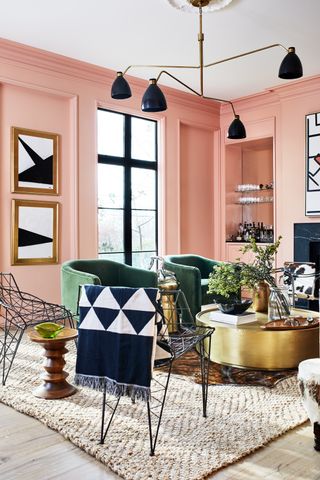 A living room with pastel pink walls, and deep green armchairs