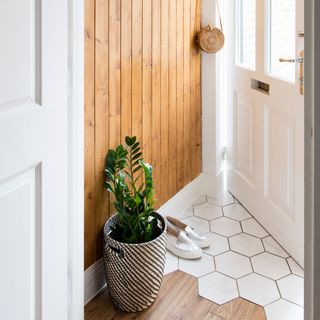 Detail shot of hallway showing wooden wall panelling and a mix of hexagon floor tiles and wood flooring