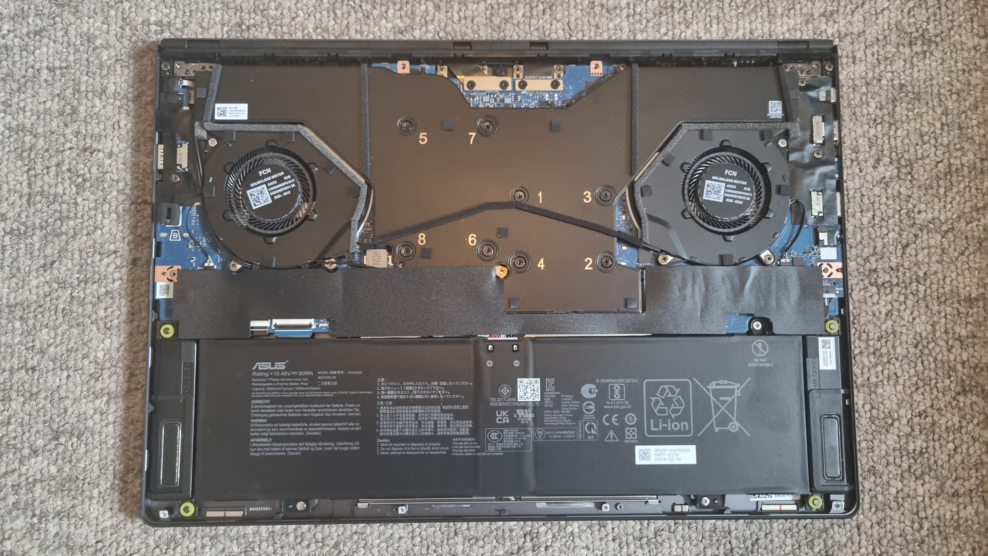 The Asus ROG Zephyrus G16 2025 with its rear panel on, and off, on a carpeted background