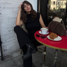 Kathryn Zahorak sitting at a red table wearing black top, black pants, and black boots