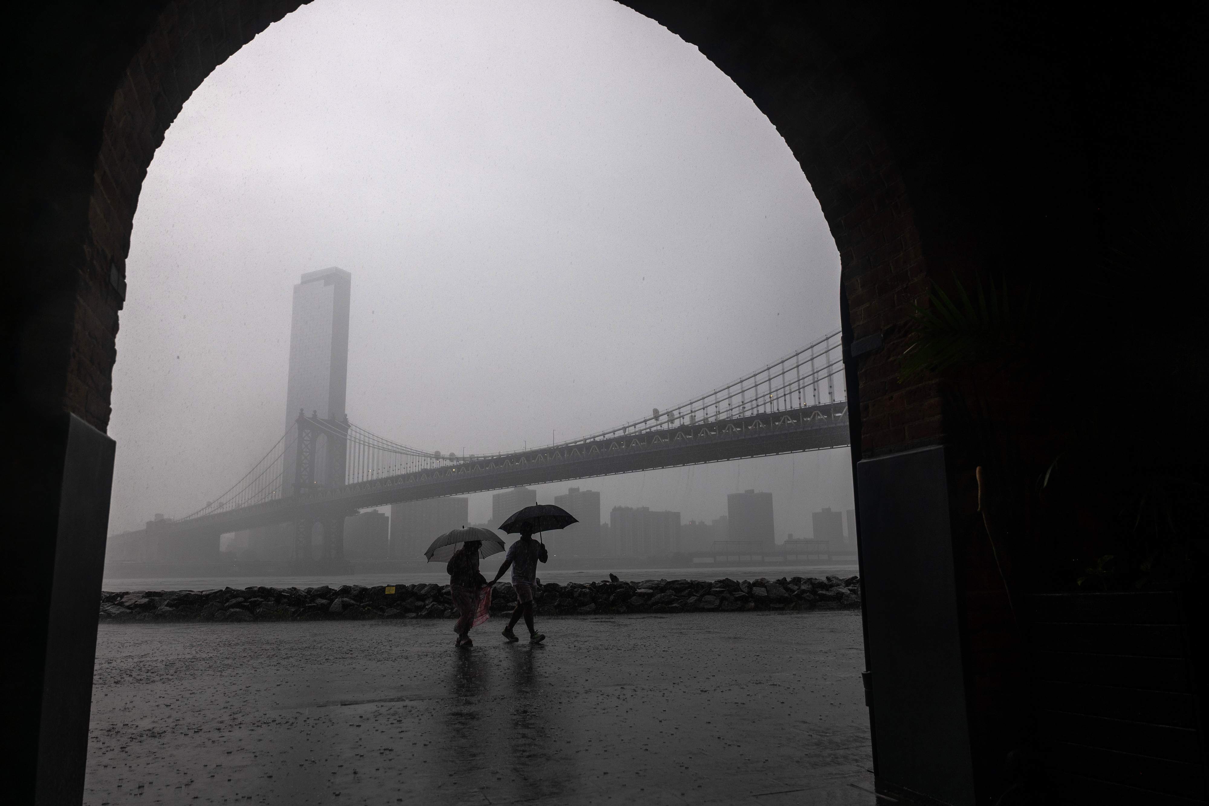 NEW YORK, NEW YORK - JULY 21: People walk through the rain in the Dumbo neighborhood in Brooklyn as severe storms move through the New York area on July 21, 2026 in New York City. New York City is under a flood watch until 2 am as the storms impact both New Jersey and New York. (Photo by Spencer Platt/Getty Images)