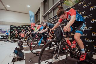 The Rouvy Skoda eMCR national championships of the Czech Republic was a Rouvy professional indoor race. This image shows the women racing on their bikes mounted to turbo trainers while looking at a screen displaying Rouvy