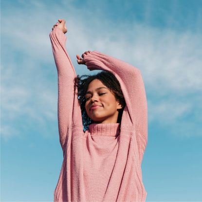 How to avoid a cold: A woman outside with her arms in the air