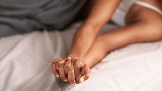 Two pairs of unrecognisable hands in bed together representing sex with an ex, one of the most common sex dreams