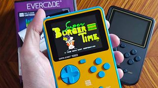 Hand holding Super Pocket Data East Edition with Super Burger Time on screen.