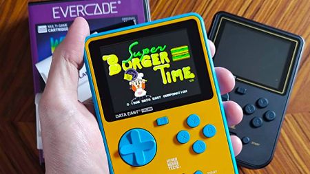 Hand holding Super Pocket Data East Edition with Super Burger Time on screen.