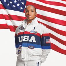 an athlete wears the ralph lauren racing jacket closing ceremony uniform for the us olympics while standing in front of an american flag