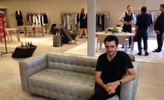 Ryan Korban sitting on a beige sofa in a mink coloured painted room