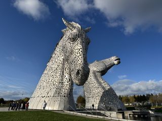 Two massive steel horse heads known as The Kelpies rise against the blue sky