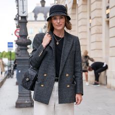 Keira Knightley wearing a bucket hat and gray coat with white pants in Paris