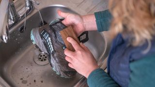 A woman cleaning hiking boots in the sink