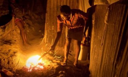 A Haitian woman lights a fire outside her home. Despite massive relief efforts, reconstruction has been uneven at best.