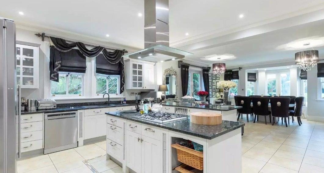 The white kitchen-diner has an island with induction hub and seating area which leads onto the patio outdoors