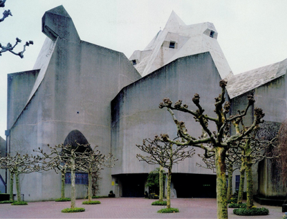Exterior view of the Pilgrimage Church. The church is made pout of concrete, including the roof. There are trees in the courtyard.