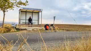 Julian Sayarer sits in a bus shelter with his bike