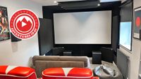 A photo of a dedicated home cinema room with red chairs and a Blade Runner poster on the wall