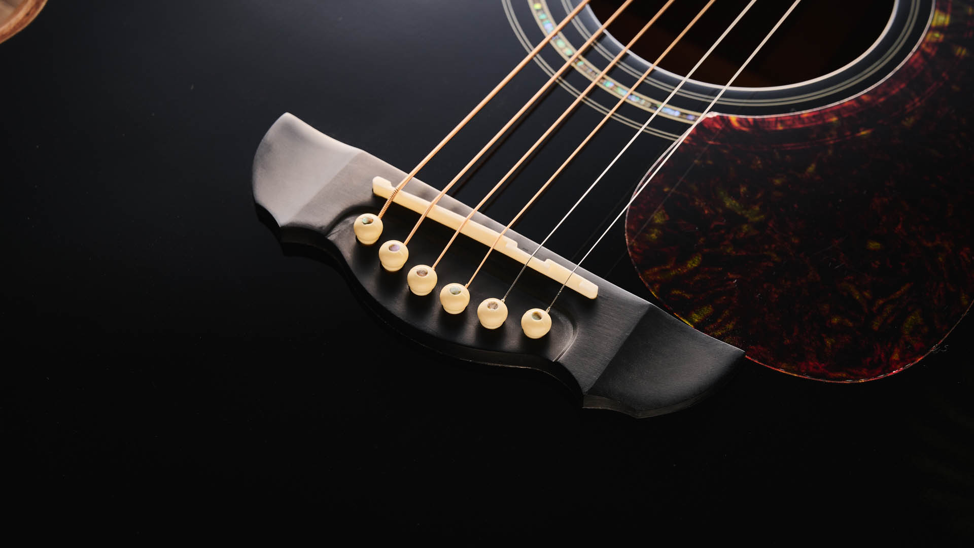 Harley Benton CLC-650SM-CE: the affordable cutaway electro-acoustic has a black top, natural back and sides, with an attractive arm-rest and tortoiseshell pickguard, and is here photographed against a wooden floor.