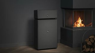 Audio Pro Drumfire II W wireless speaker in black next to a fireplace