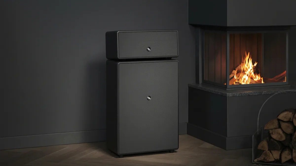 Audio Pro Drumfire II W wireless speaker in black next to a fireplace