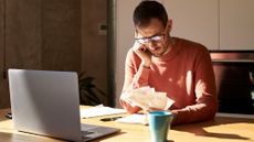 Stressed man examining his financial bills while sitting at a desk