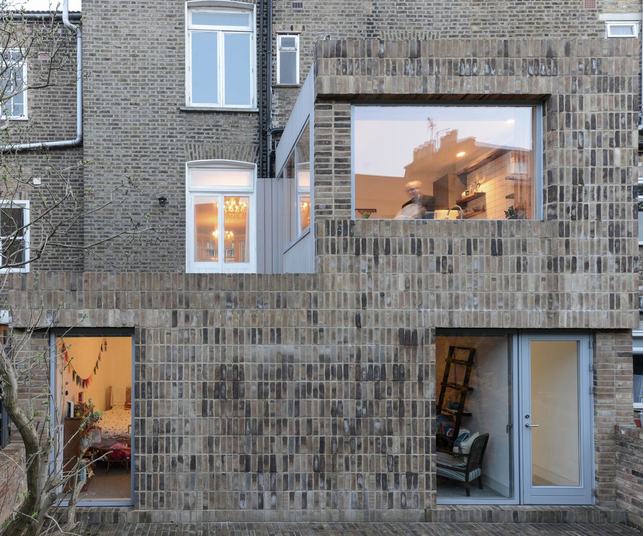 front view of double storey timber frame extension with brick cladding to font and large aluminium framed windows and doors