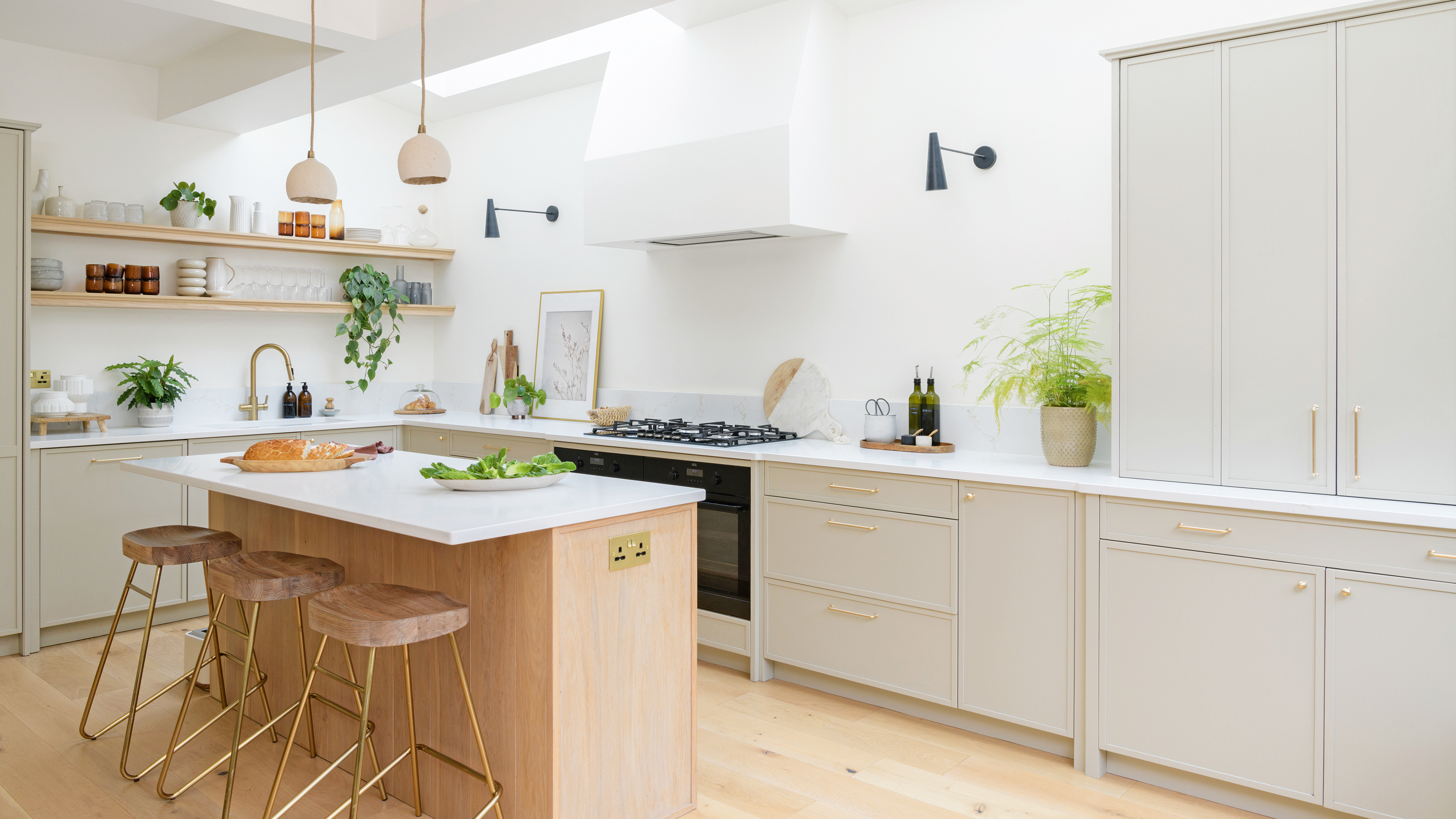 a bright and airy open plan kitchen with wooden flooring and a wooden kitchen island with pale worktops and neutral cabinetry