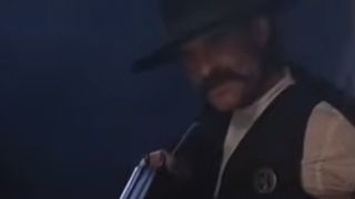 Kurt Russell wearing a black hat and badge in Tombstone