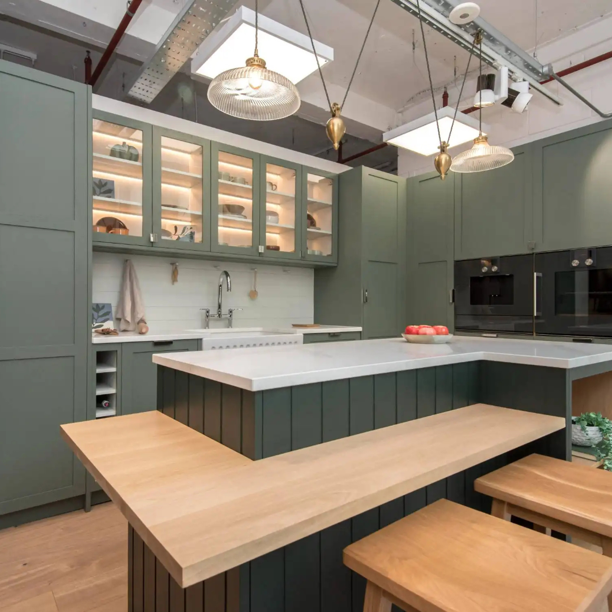 a green painted kitchen with oak worktop and bar stools