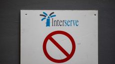 Interserve logo on a sign at a construction site with a red 'no entry' symbol beneath it