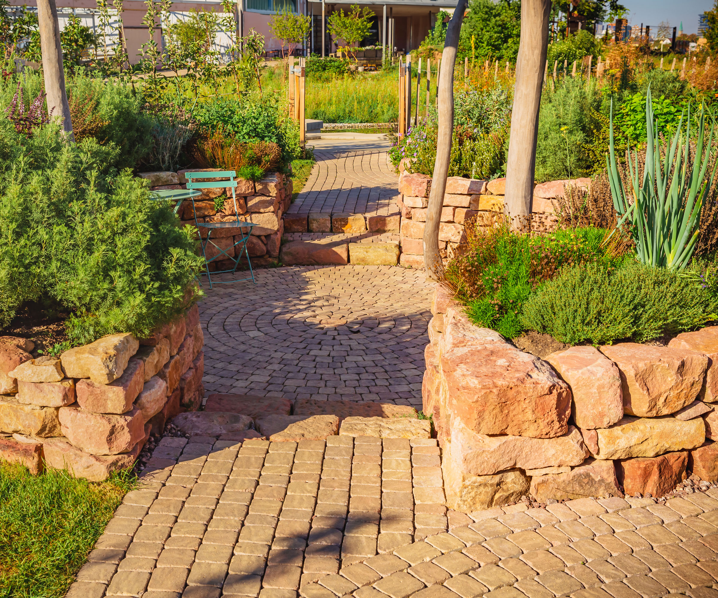 circular brick patio with brick wall, planting, trees and garden chair