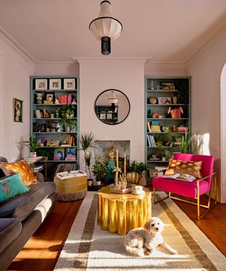Playful, Miami-style living space with brass scalloped coffee table focal point, and open shelves styled with color-coordinated books and quirky objects