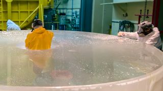 A man stands in the middle of a large metal circle with two other men standing on either side of him.
