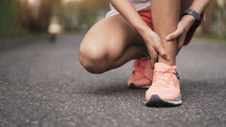 女子跑步者疼痛地抱着脚踝