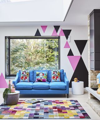 Blue sofa in conservatory with colorful rug and wall decor