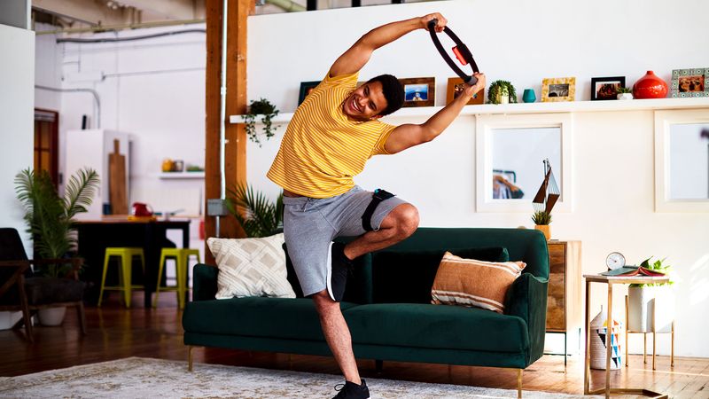 A man training holding the Ring Fit controller above his head