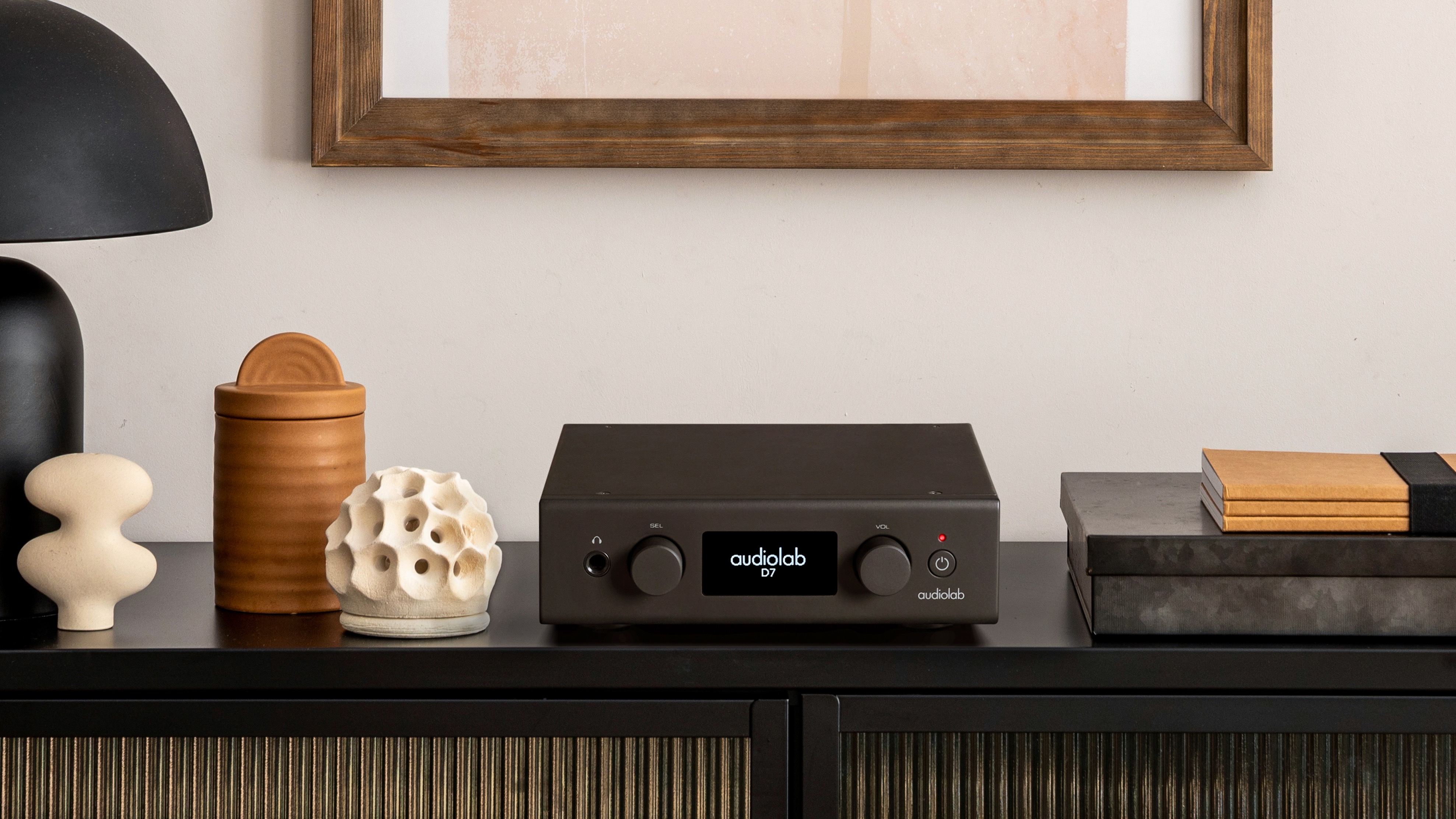 Audiolab D7 DAC in black finish, placed on sideboard with a variety of decor
