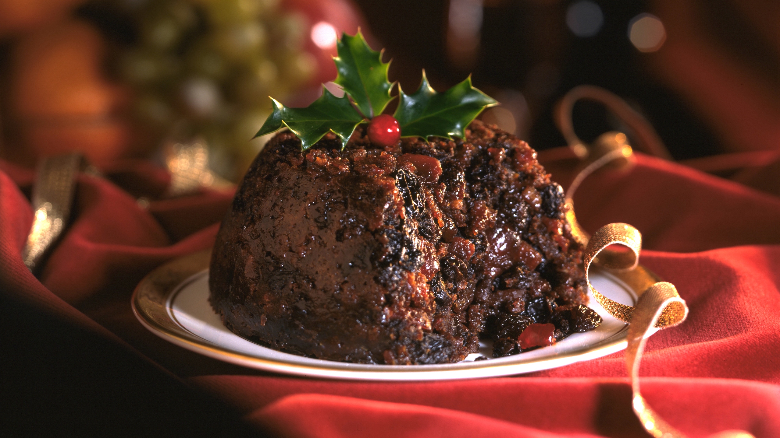 Christmas Pudding decorated with holly leaves on red background