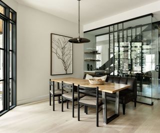 dining space with glass box bar and wine store and wooden table and floors