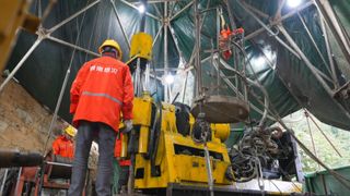 A miner stands next to the drill