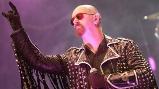 Rob Halford onstage with Judas Priest and throwing the ‘metal horns’ in 2005