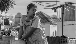 Roma Yalitza Aparicio looking over her shoulder as she does the laundry