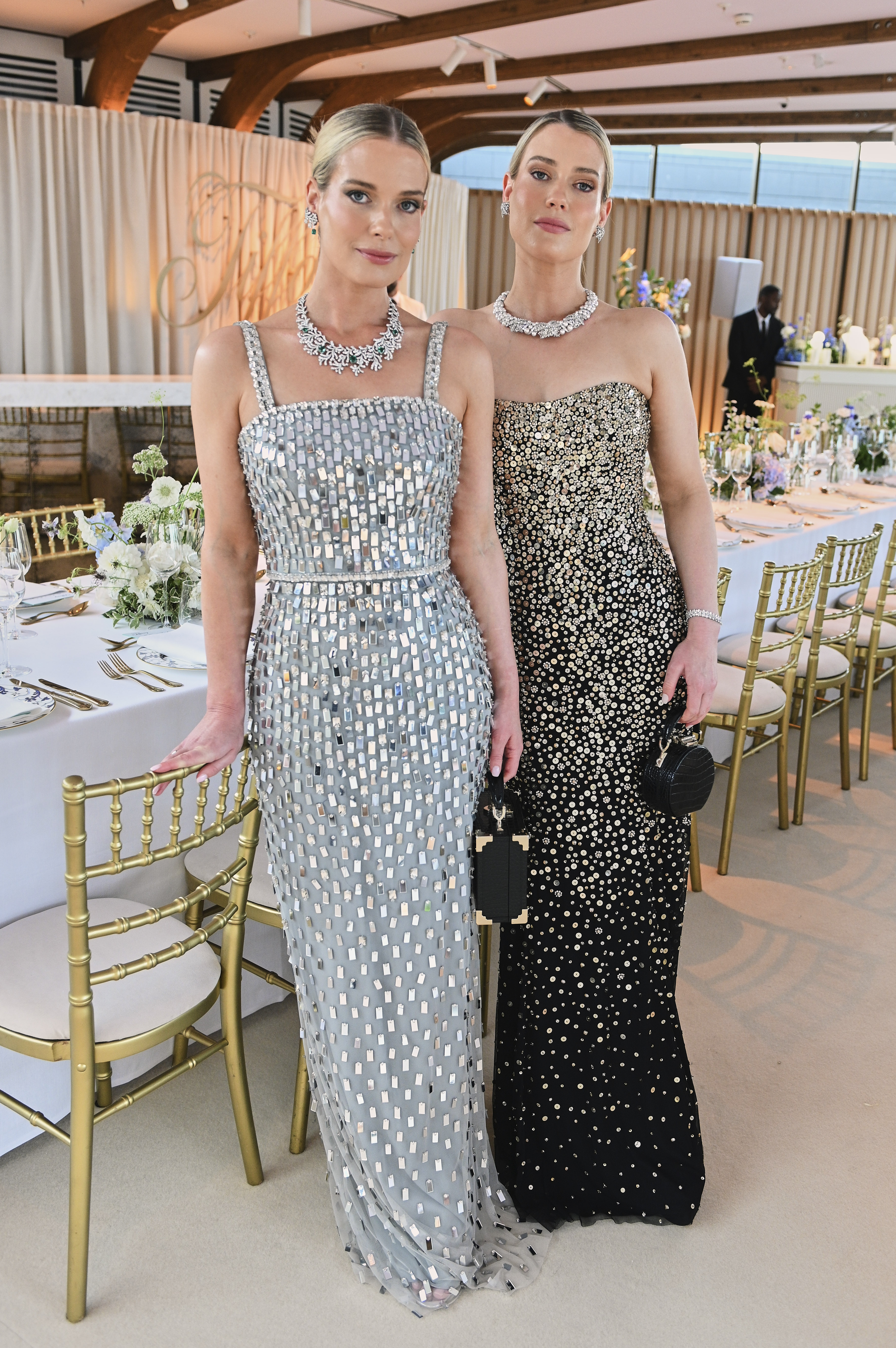 Amelia and Eliza Spencer wearing sequined evening gowns standing in front of a dinner table