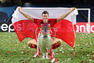 Robert Lewandowski poses with the Champions League trophy and a Poland flag after Bayern Munich's win over Paris Saint-Germain in the 2020 final.